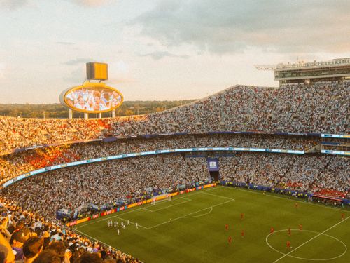 Free Aerial view of a packed soccer stadium during a lively match at sunset. Stock Photo