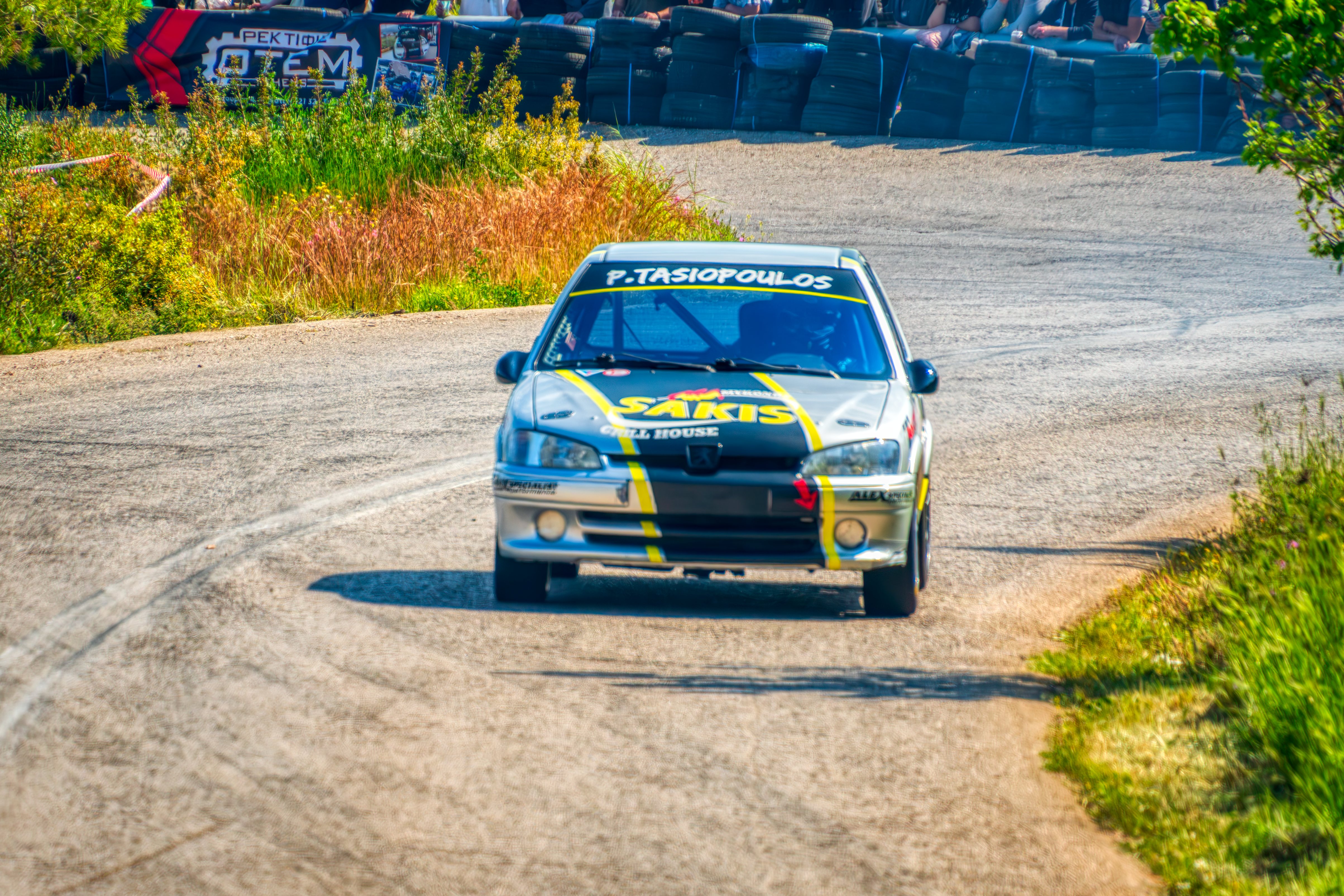 Rally car speeding along a country road during a race.