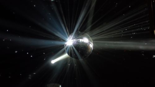 Free A disco ball reflecting beams of light in a dark nightclub setting, creating a vibrant party atmosphere. Stock Photo