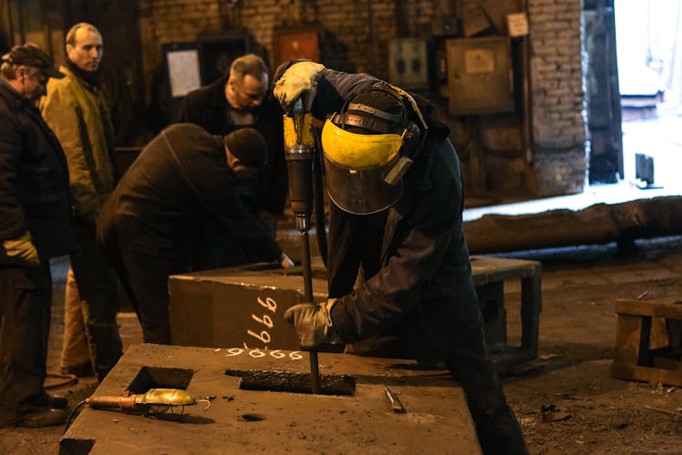 Anonymous Craftsman Fixing Metal Construction While Working In Factory With Colleagues