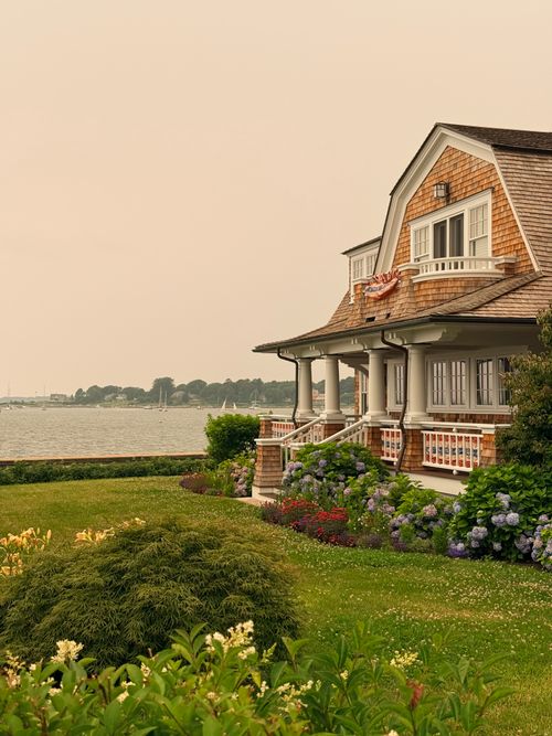 Free Cozy coastal cottage by the water in Stonington, CT, with lush garden and American flag. Stock Photo
