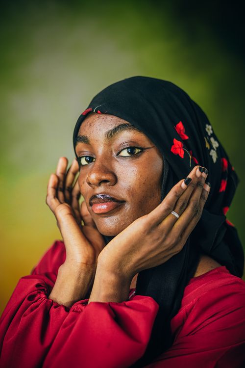 Free Close-up portrait of a woman in a black and red headscarf against a colorful backdrop. Stock Photo