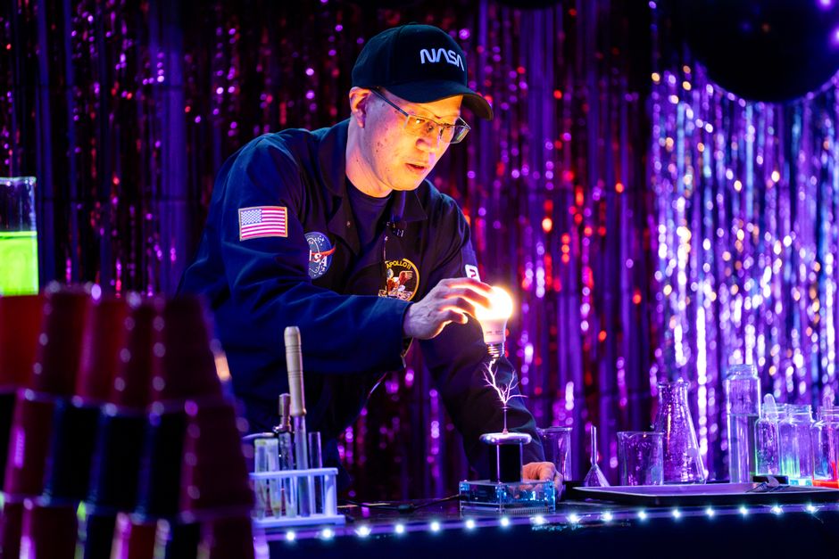 A scientist conducts an electricity experiment with a glowing light bulb in a laboratory setting.