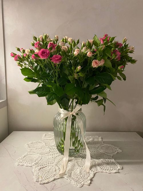 Free Beautiful bouquet of pink and white roses in a glass vase on a doily, perfect for decor. Stock Photo