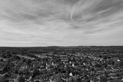Free Aerial black and white photo of a typical English suburban neighborhood showcasing rooftops and vast landscapes. Stock Photo