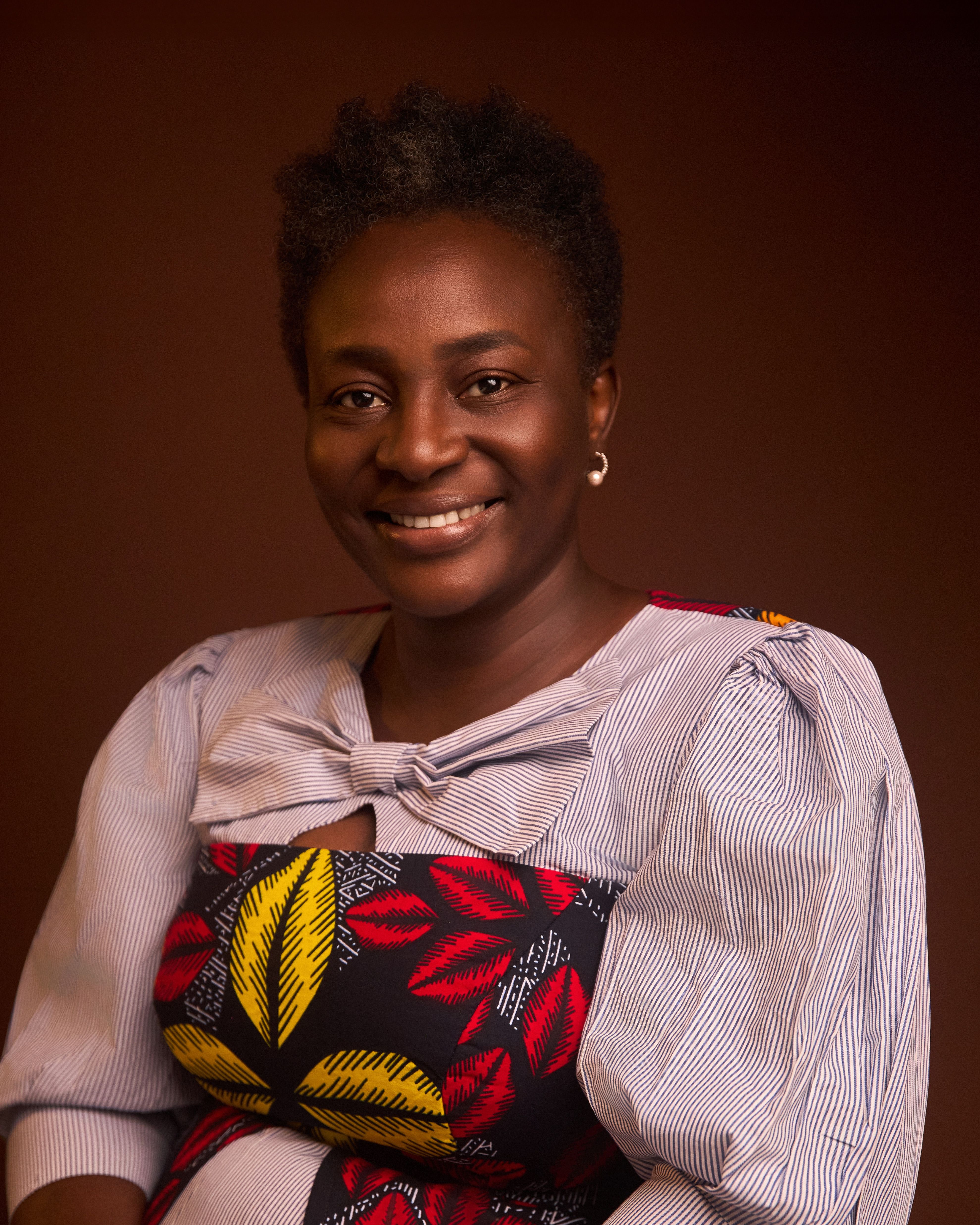 Elegant portrait of a woman in traditional African attire, smiling warmly.