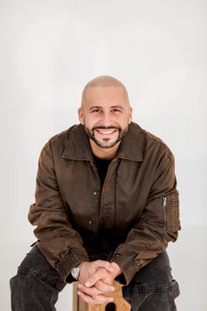 A cheerful man seated and smiling warmly in a casual setting.
