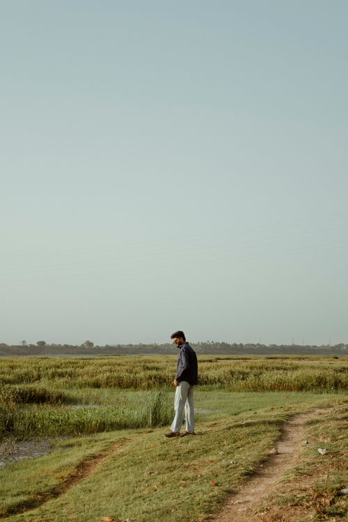 Free Peaceful scene of a man walking by a grassy riverbank, evoking calm and serenity in nature. Stock Photo