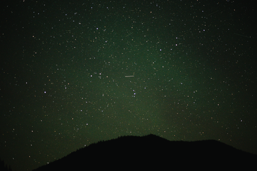 Free A beautiful starry night sky with a mountain silhouette beneath the twinkling stars. Stock Photo