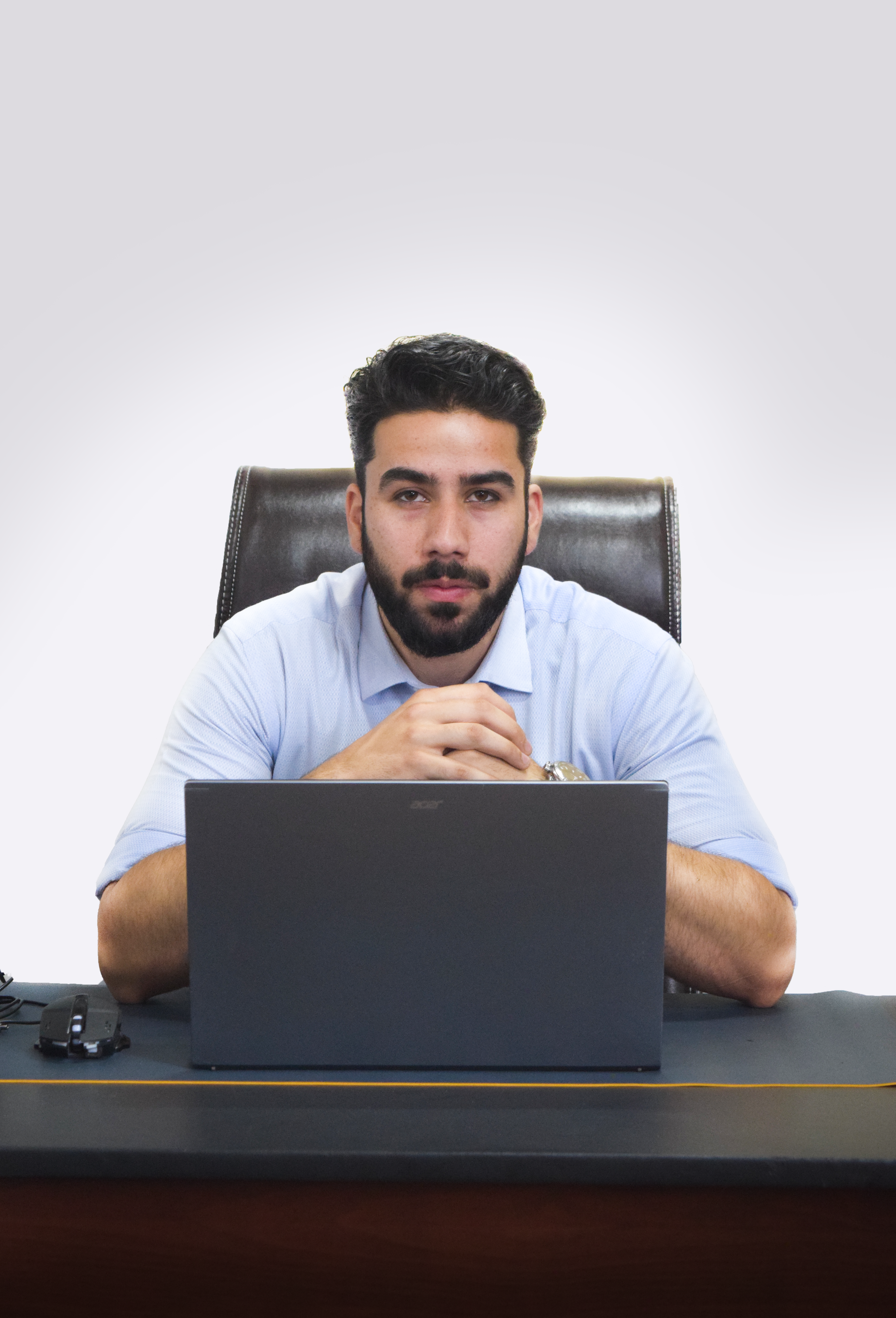 Young businessman sitting at desk with laptop, portraying professionalism and confidence.