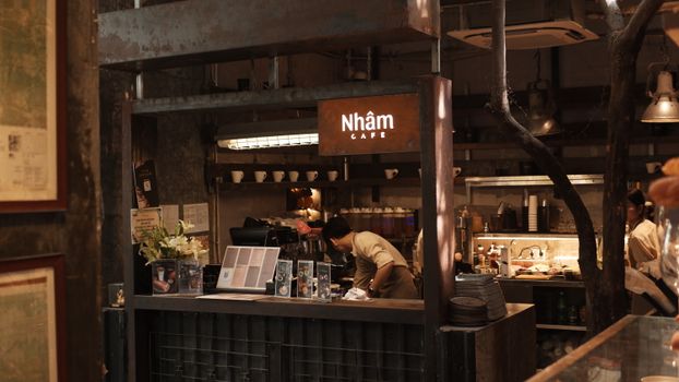 Industrial-style cafe with barista preparing drinks indoors at Nhâm Cafe.