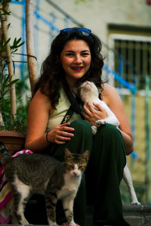 Free Happy woman sitting outside with two cats, enjoying a sunny day. Stock Photo