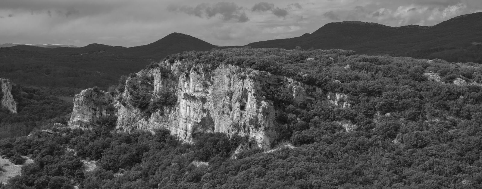 Black and white aerial shot capturing the dramatic rocky cliffs and forests of southern France.