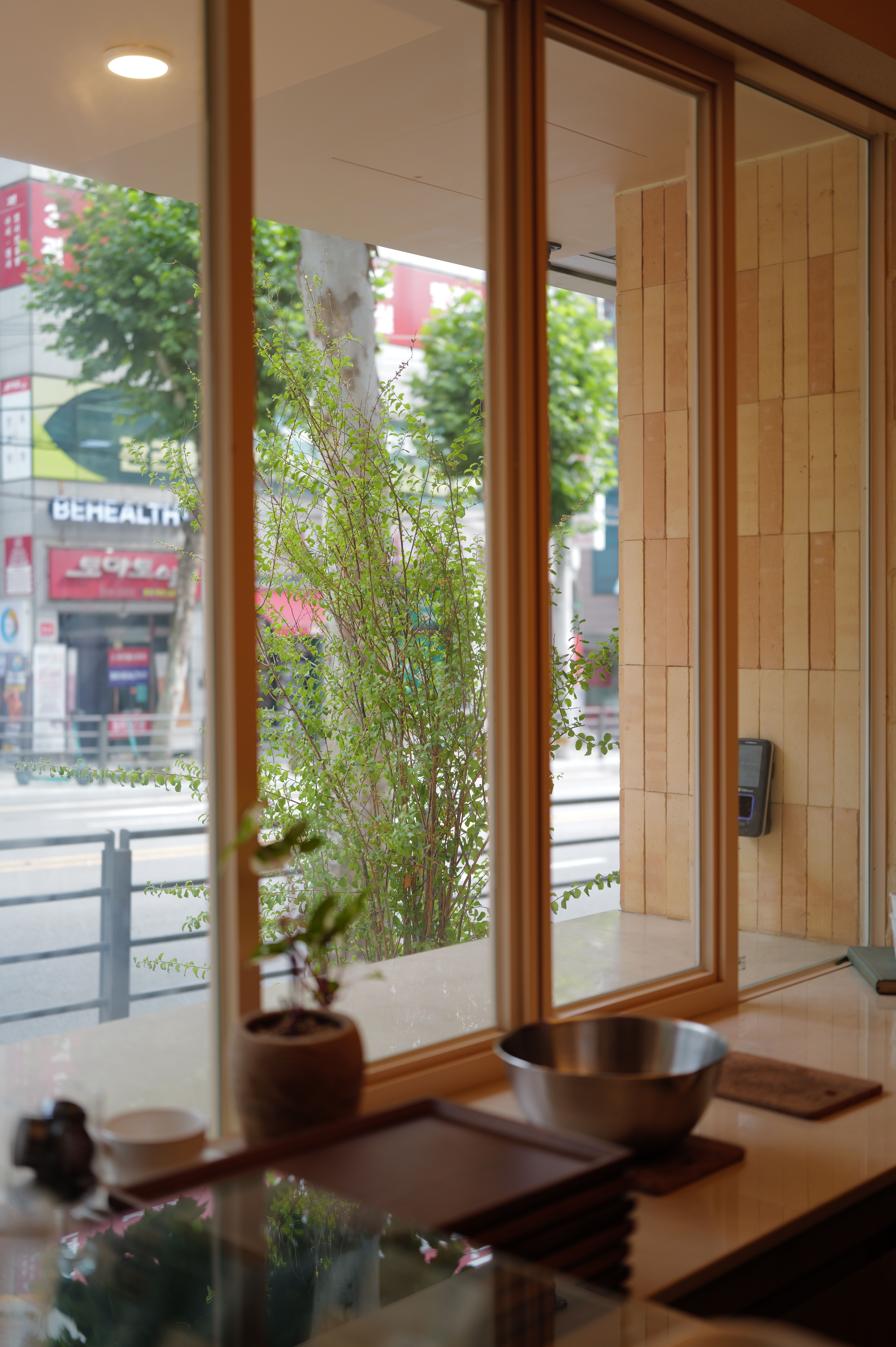 Warm cafe interior showing street view through large windows on a sunny day.