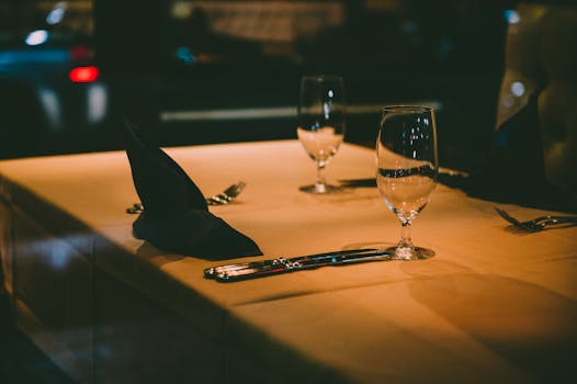 Elegant restaurant table setting with cutlery and wine glasses under warm lighting.