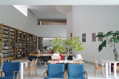 Free A spacious library interior showcasing shelves full of books, cozy seating, and indoor plants. Stock Photo
