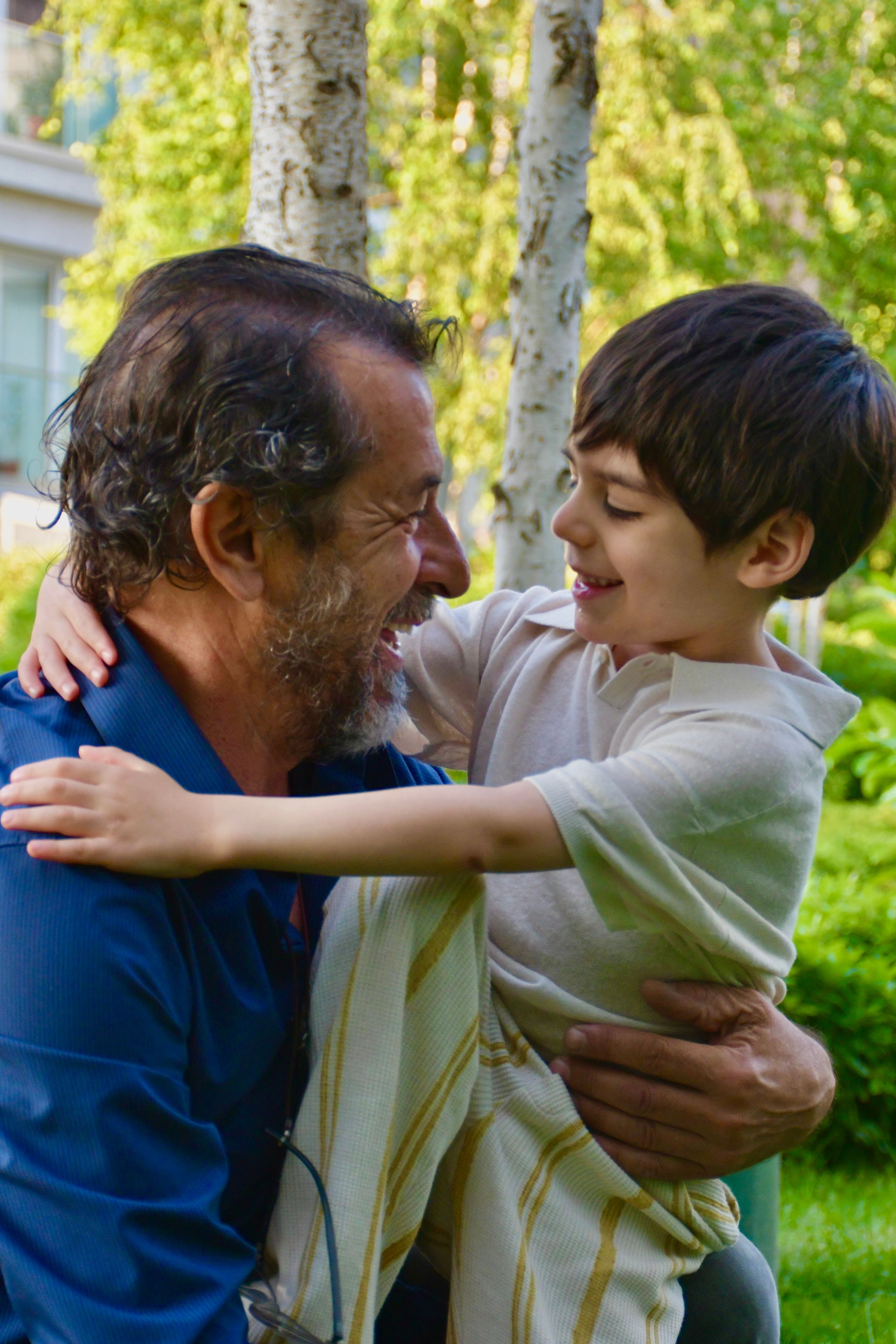 A loving moment of a father and son hugging in a lush green park. Ideal for family and nature themes.