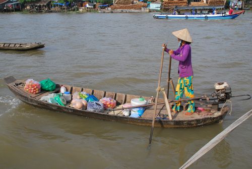 Free A local vendor navigates a riverboat selling goods in Vietnam, showcasing traditional river life. Stock Photo