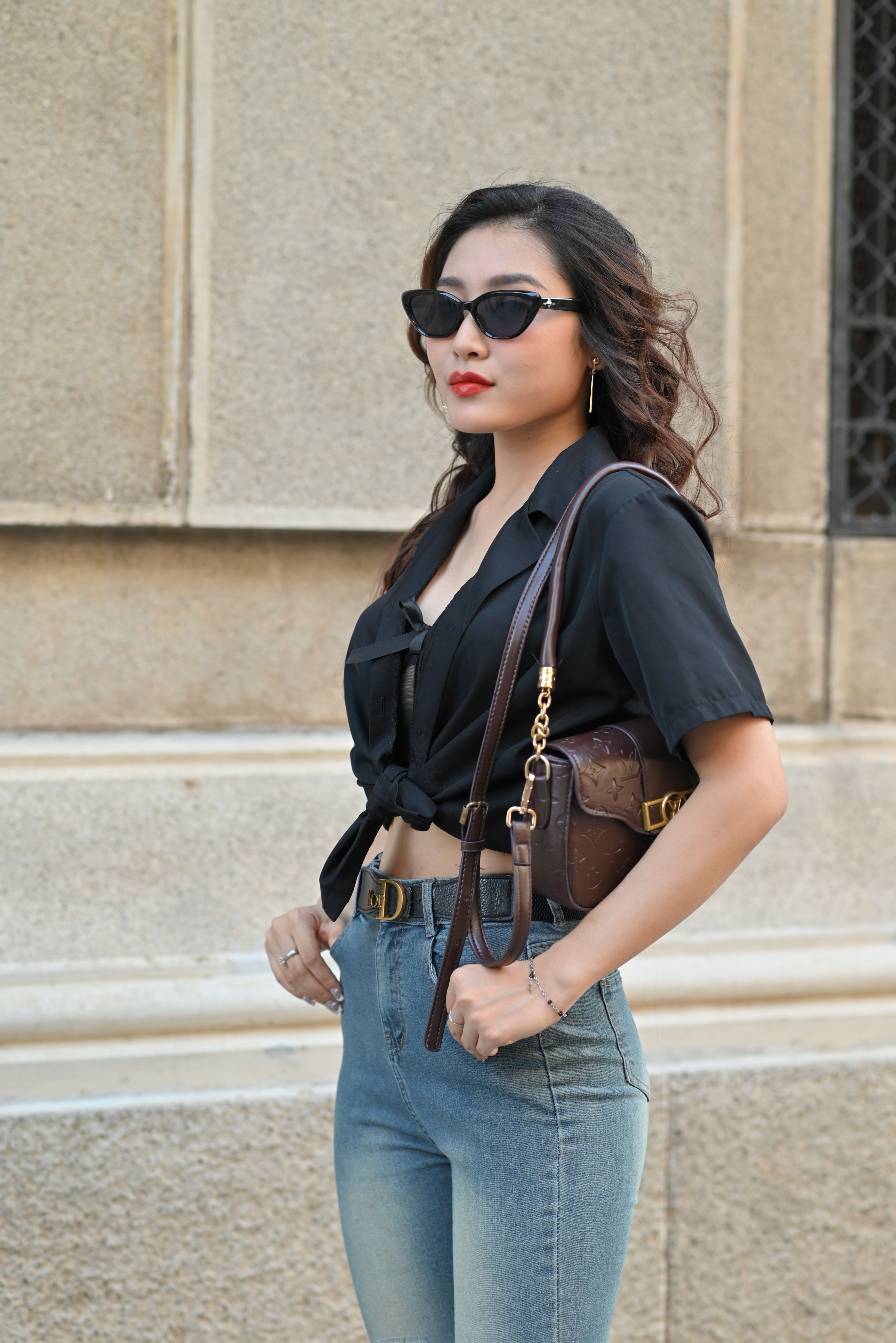 Chic woman in an urban setting wearing a black top, sunglasses, and jeans, exuding confident style. - Local Resources for Verification