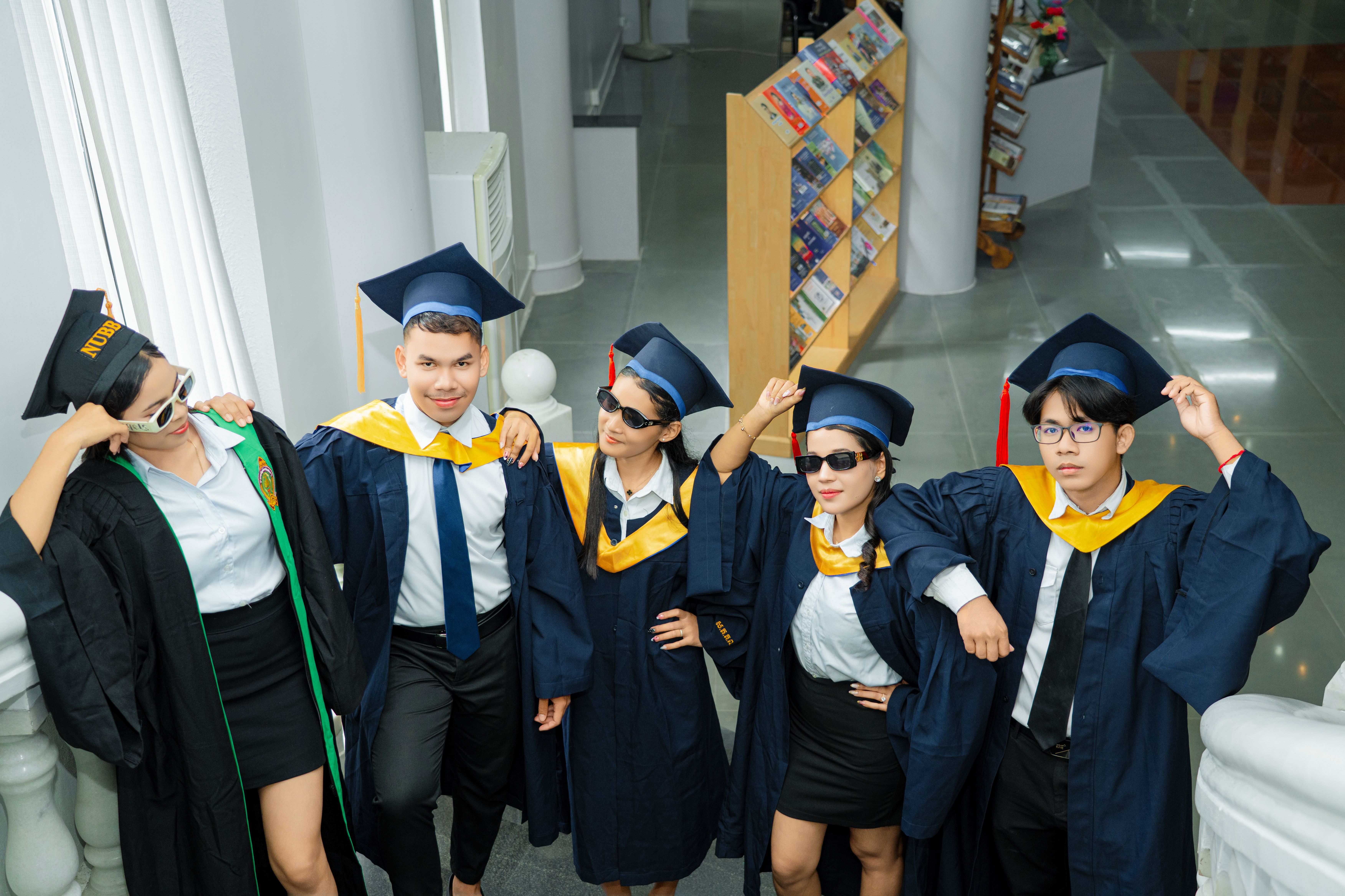 Group of young graduates posing indoors in cap and gown, celebrating their achievement with confidence