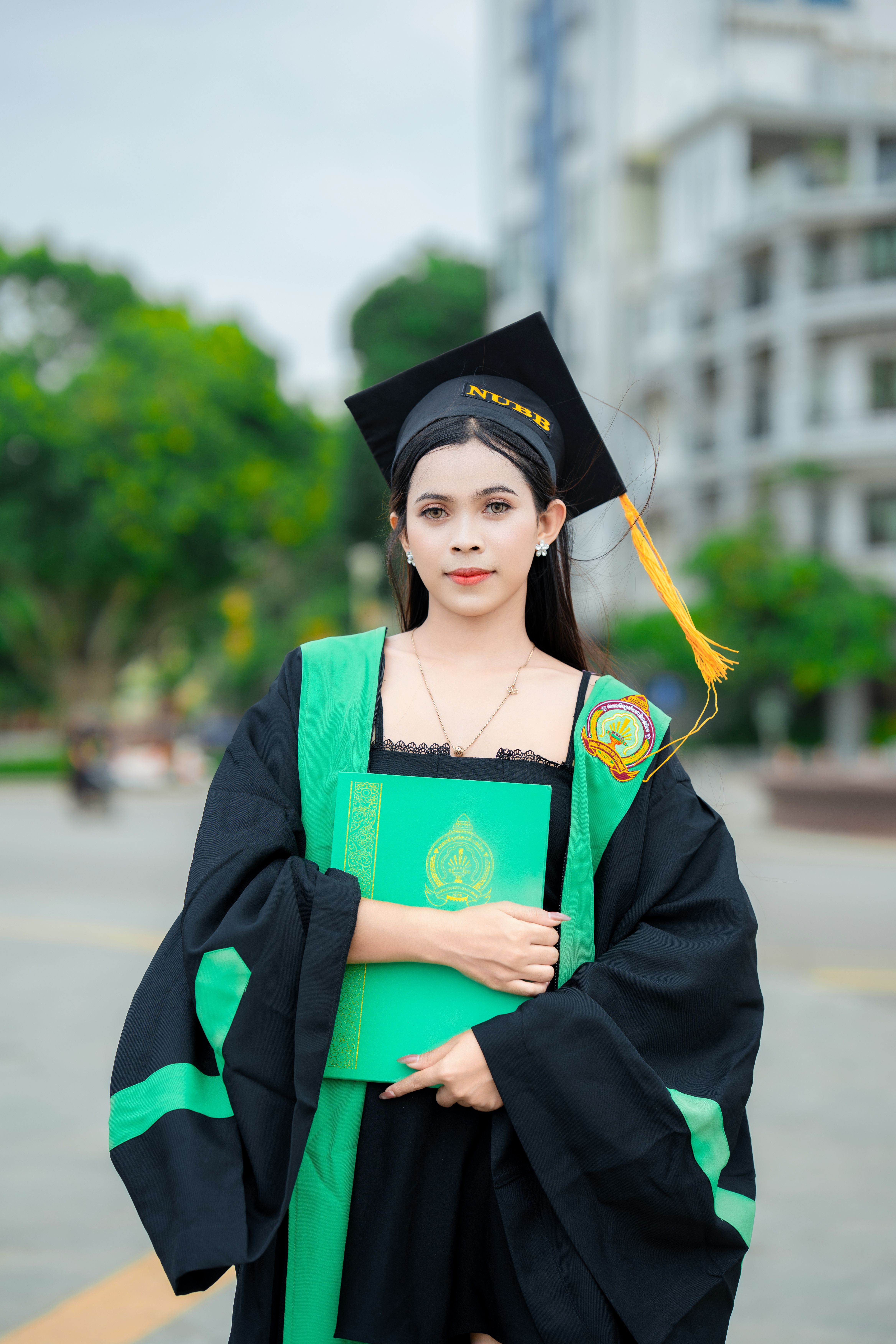 Young Cambodian woman celebrates graduation outdoors in Battambang, Cambodia.