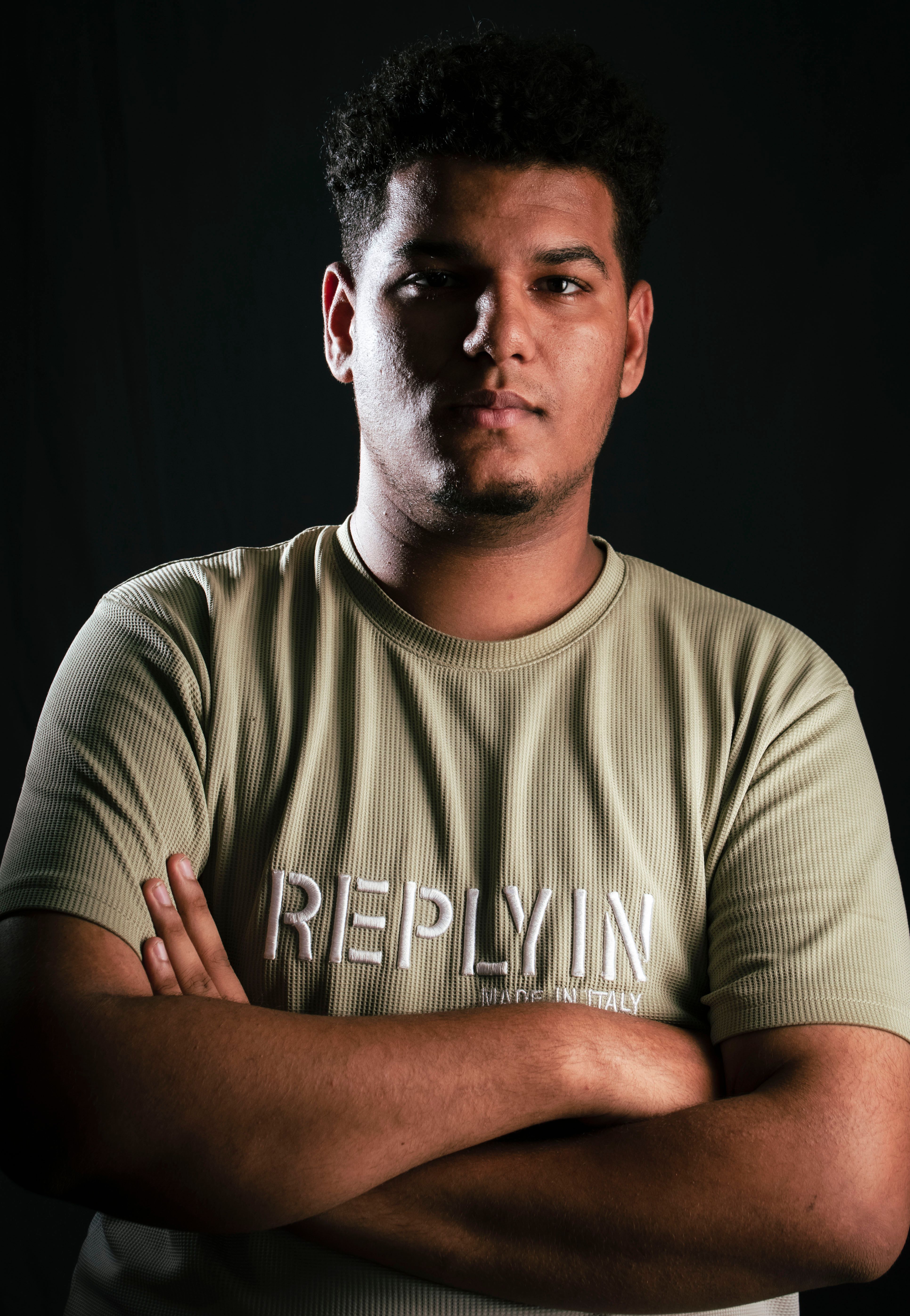 Confident young man posing with crossed arms in a studio setting.