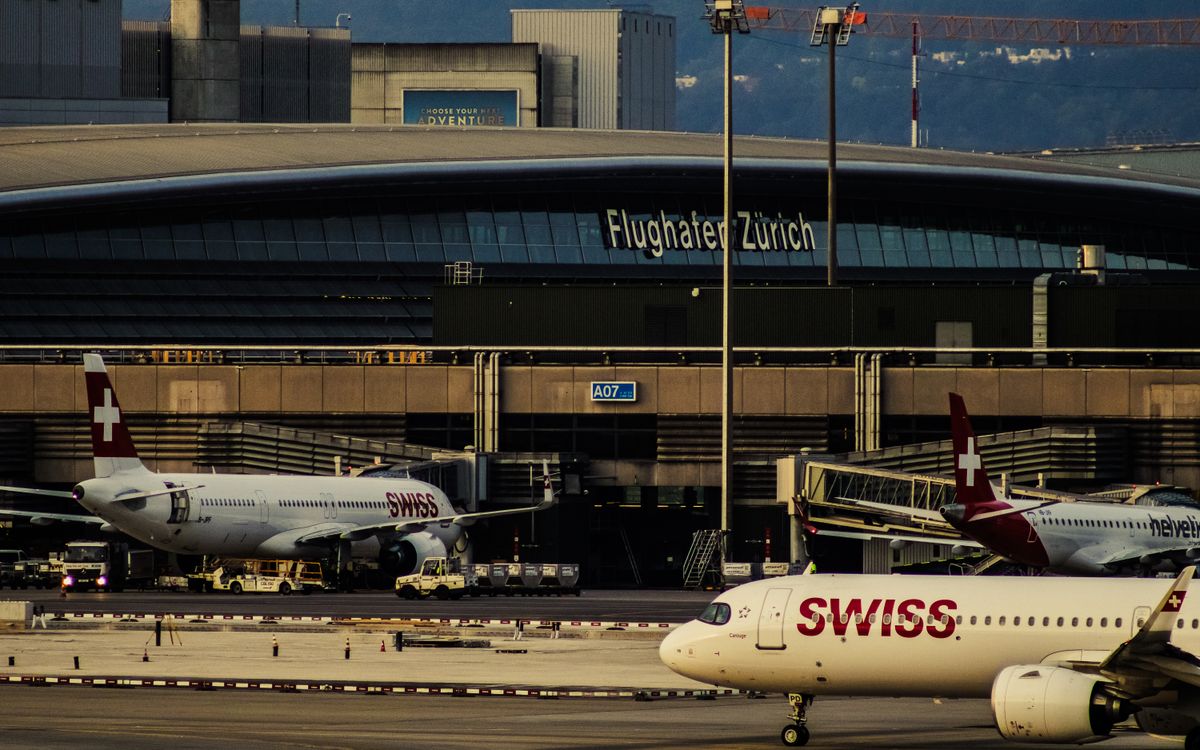 Swiss Airlines planes parked at Zurich Airport with clear view of terminal building.