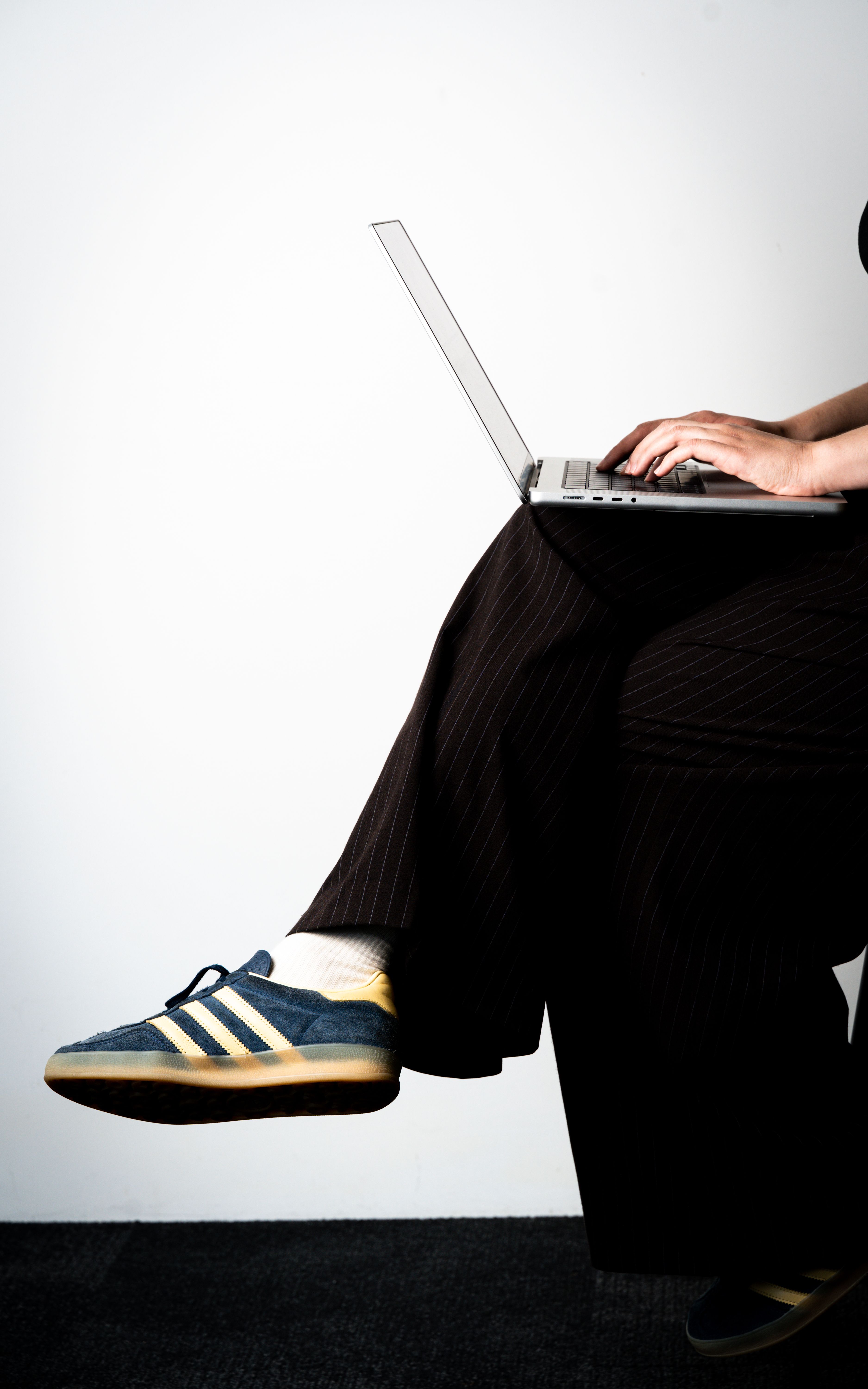 A person working on a laptop wearing casual sneakers, blending modern business and casual style.