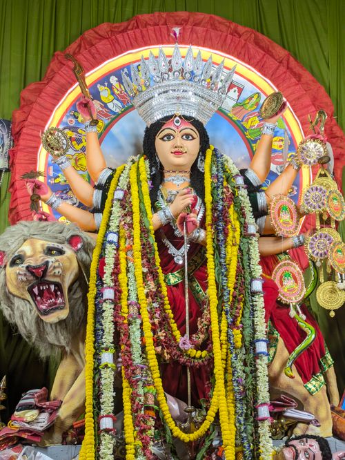 Free Intricately adorned Durga idol with vibrant garlands, lion, and traditional weaponry during Durga Puja. Stock Photo