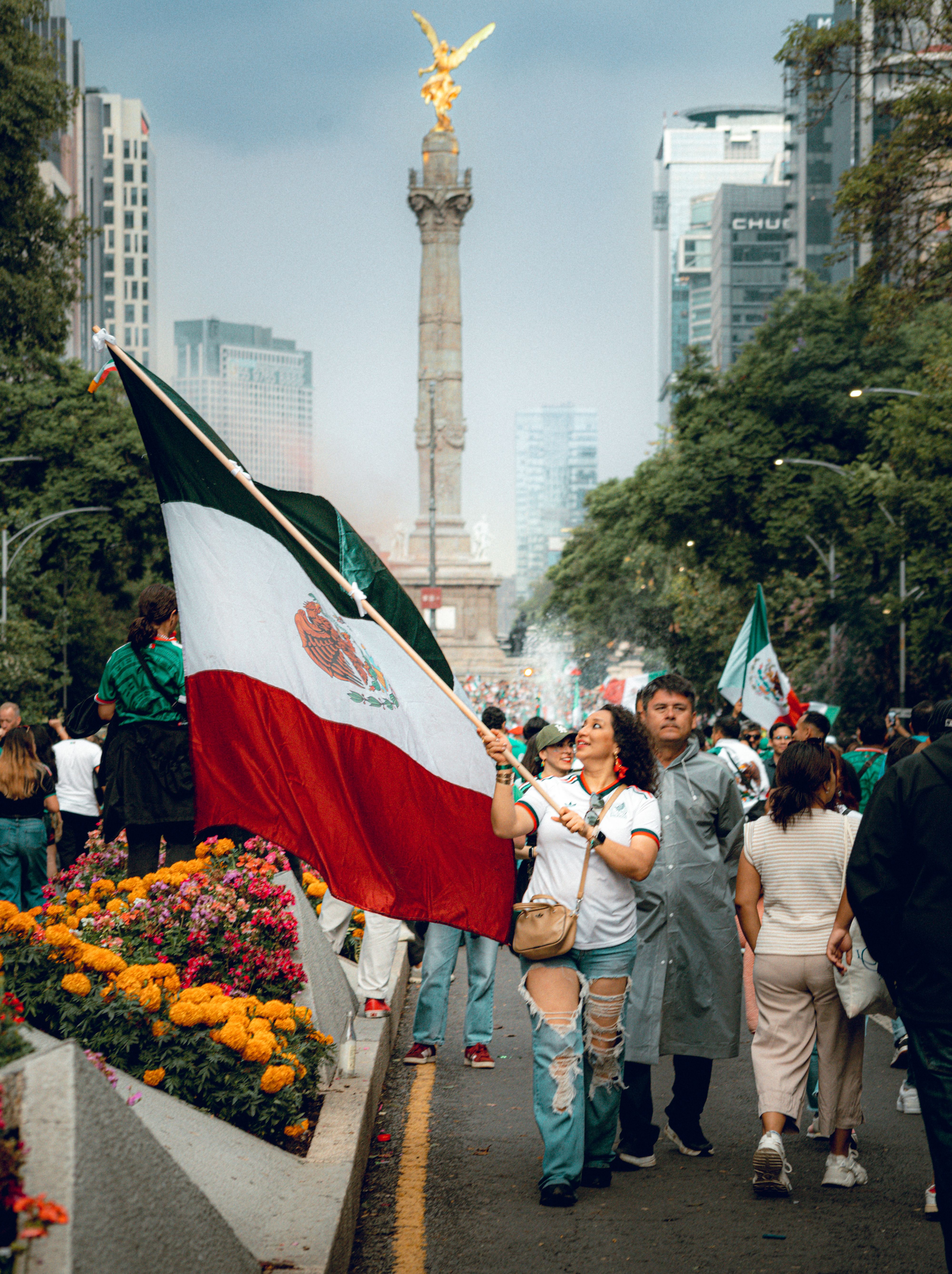 Citizens parade with flags on Avenida Reforma in Mexico City, displaying national pride.