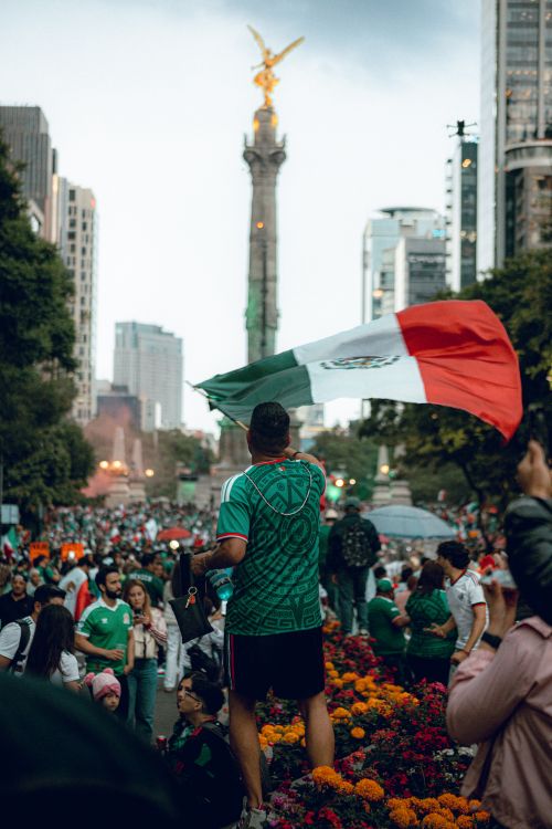 Free Crowds gather around the Angel of Independence in CDMX, waving Mexican flags during a celebration. Stock Photo