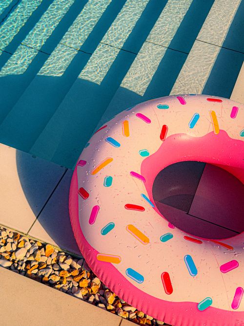 Free Vibrant inflatable donut floater next to a pool under the summer sun. Stock Photo