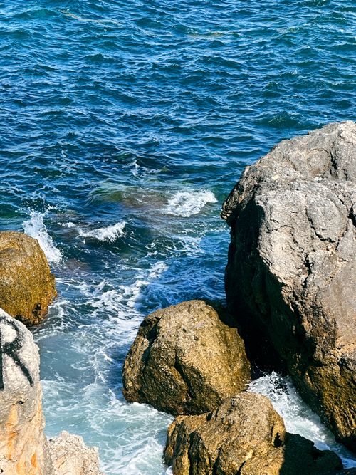 Free Clear ocean waves crashing against rugged rocks on a sunny day. Stock Photo