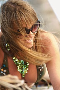 Smiling woman in sunglasses enjoying a sunny day at Miami Beach, Florida.