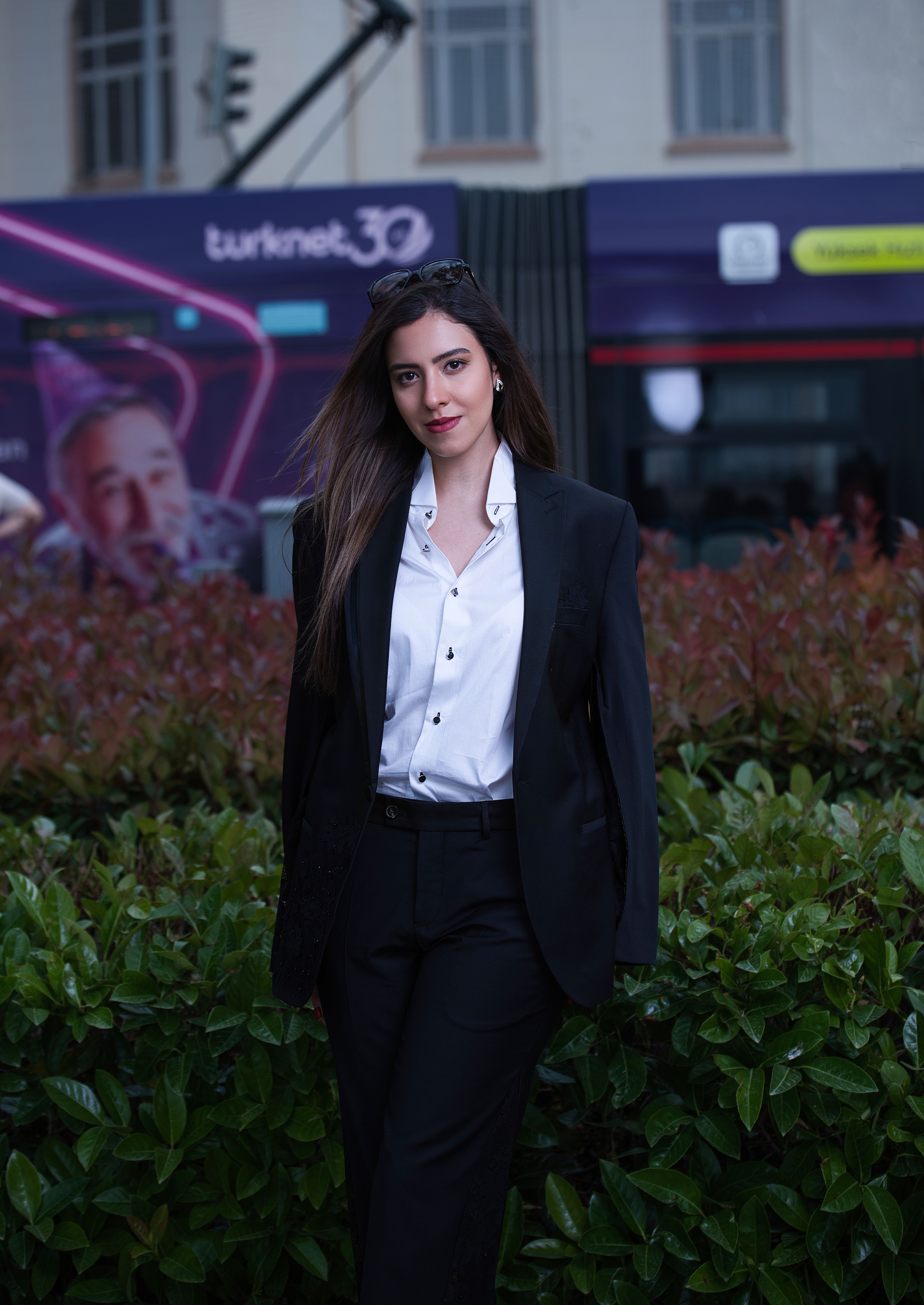 A professional woman in a suit stands confidently in an urban environment.