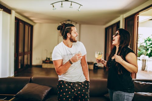 Free Young man and woman in casual outfit smiling and looking at each other while having fun at home during romantic meeting on daytime Stock Photo