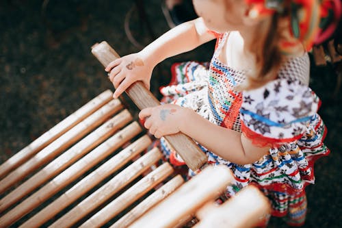 屋外の木製の椅子の近くで遊ぶ少女