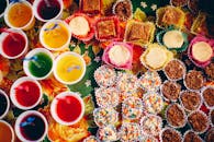 彩色什锦糖果和果冻杯在花卉桌布上的顶视图