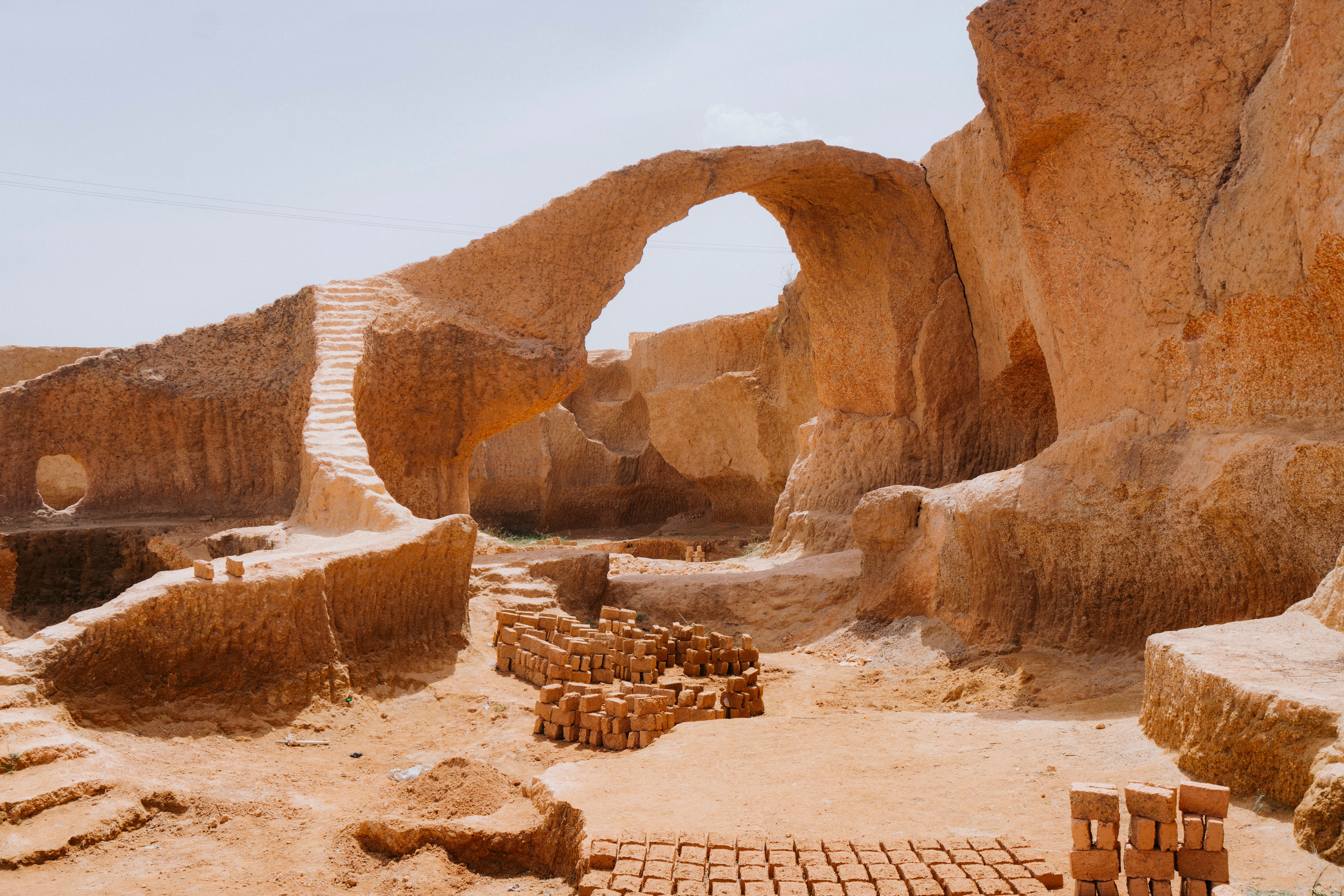 Scenic view of a natural stone archway in a desert quarry with brick formations.