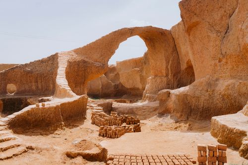 Free Scenic view of a natural stone archway in a desert quarry with brick formations. Stock Photo