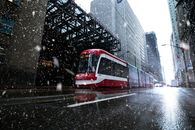 一辆多伦多有轨电车在冬日市中心的建筑下，沿着积雪的街道行驶
