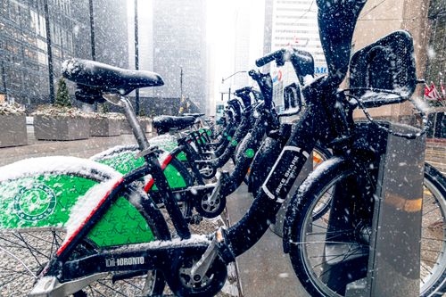Free Bike share station covered in snow during winter in downtown Toronto, showcasing urban commuting in cold weather. Stock Photo