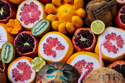 Free Colorful display of various fruits including grapefruit, pomegranate, coconuts, and citrus in a vibrant market setting. Stock Photo