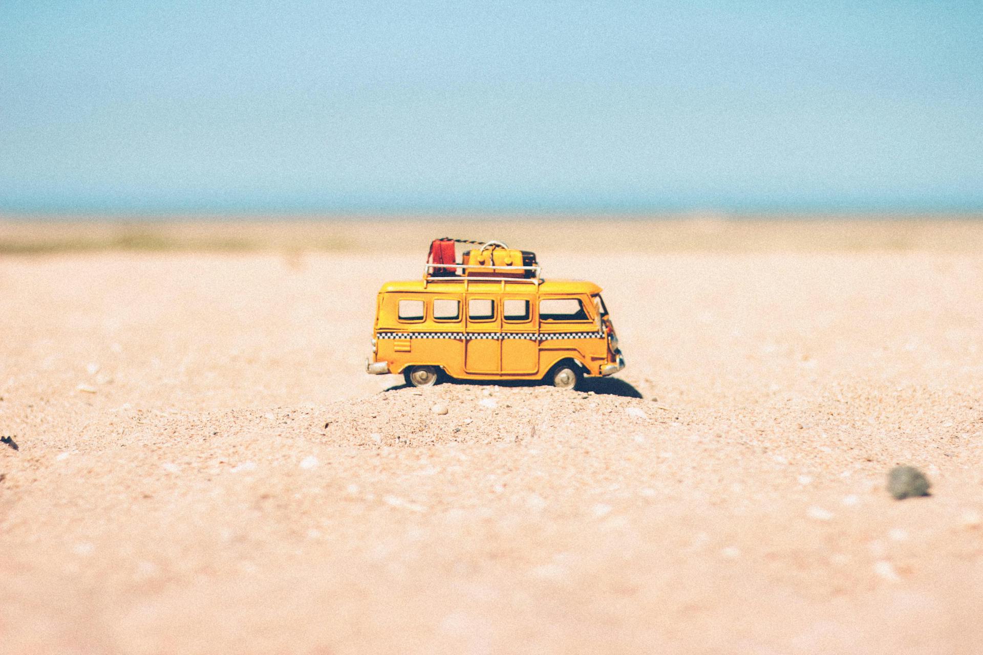 Gele giet-miniatuurbus op bruin zand