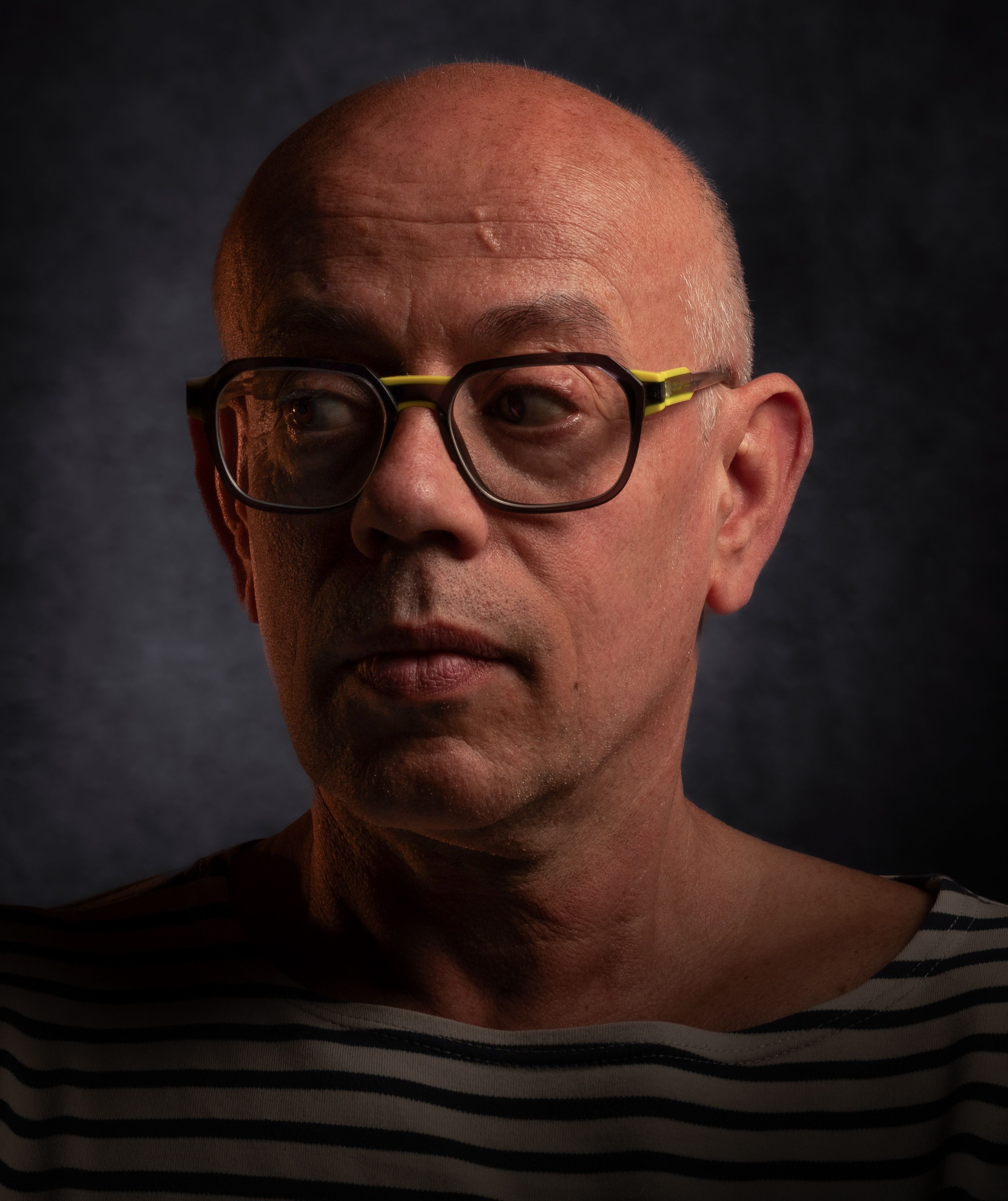Close-up portrait of a middle-aged man wearing glasses and a striped shirt.