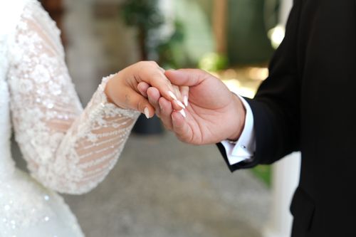 Free Close-up of a bride and groom holding hands, showcasing elegant attire and intimate connection. Stock Photo