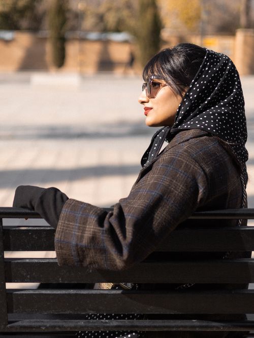 Free Fashionable woman in sunglasses sitting on a park bench in Berlin, Germany Stock Photo