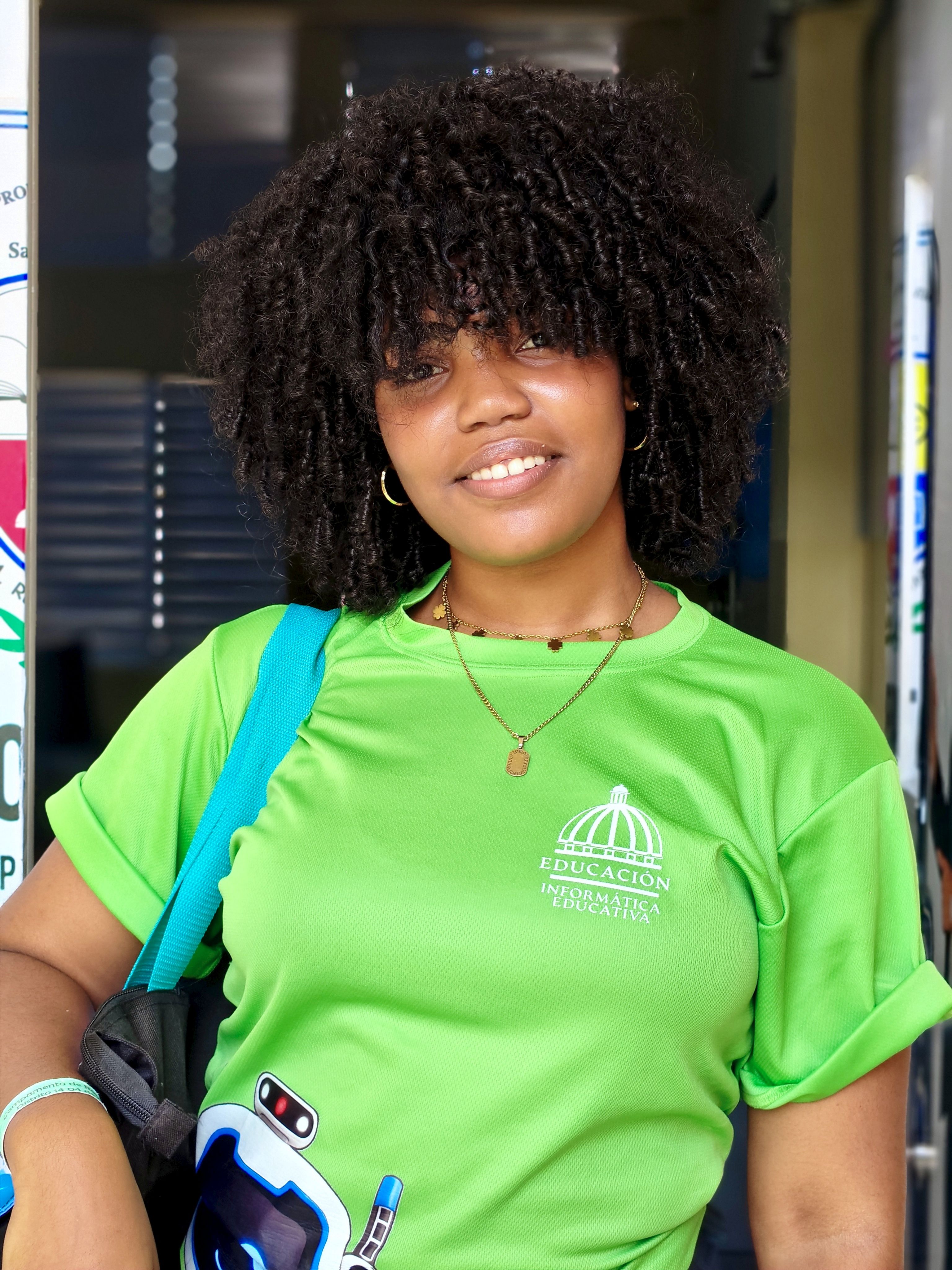 Portrait of a smiling young woman indoors, wearing a vibrant green t-shirt, exuding confidence and warmth.