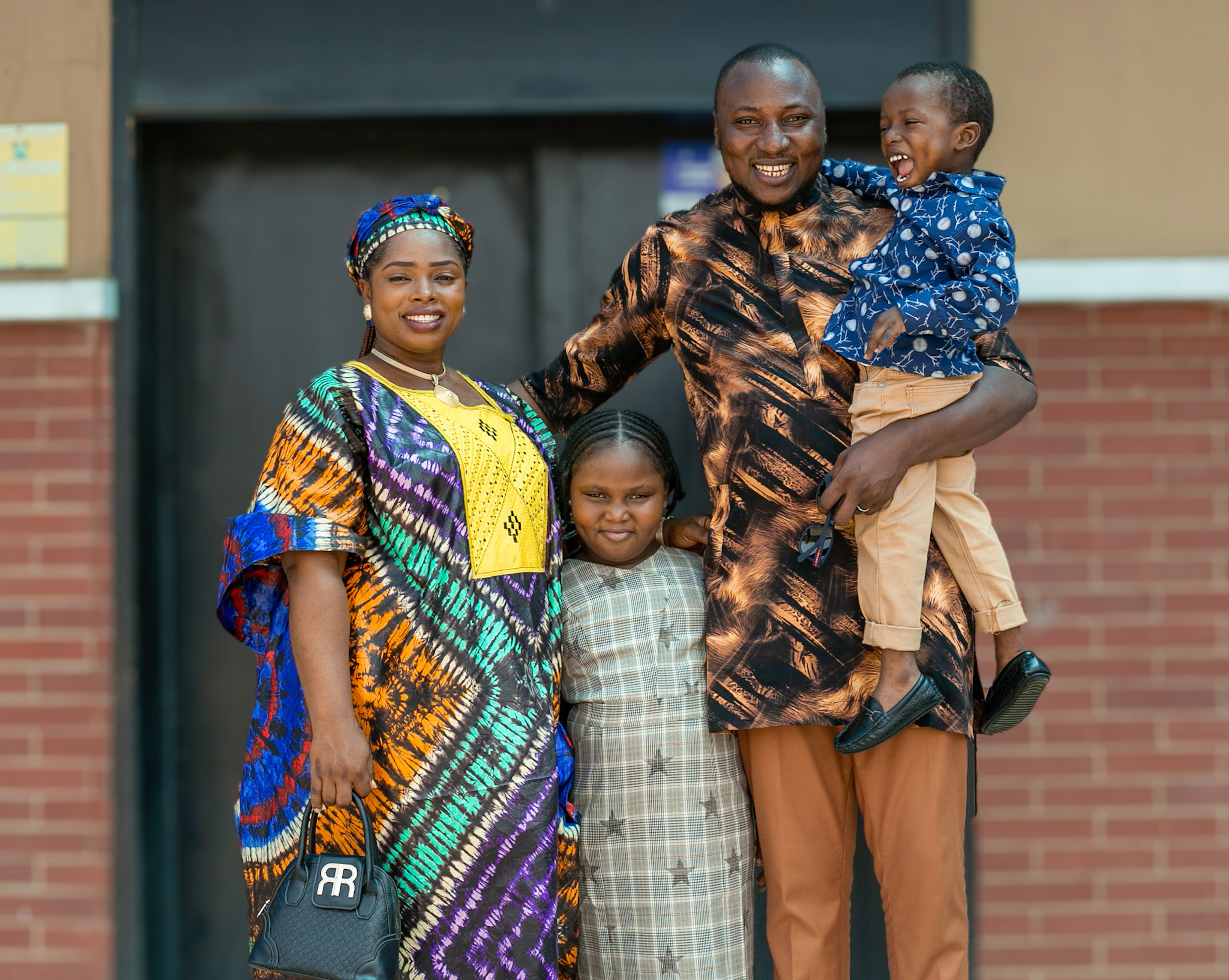 A joyful African family dressed in traditional clothing, smiling outdoors in Lagos, Nigeria.