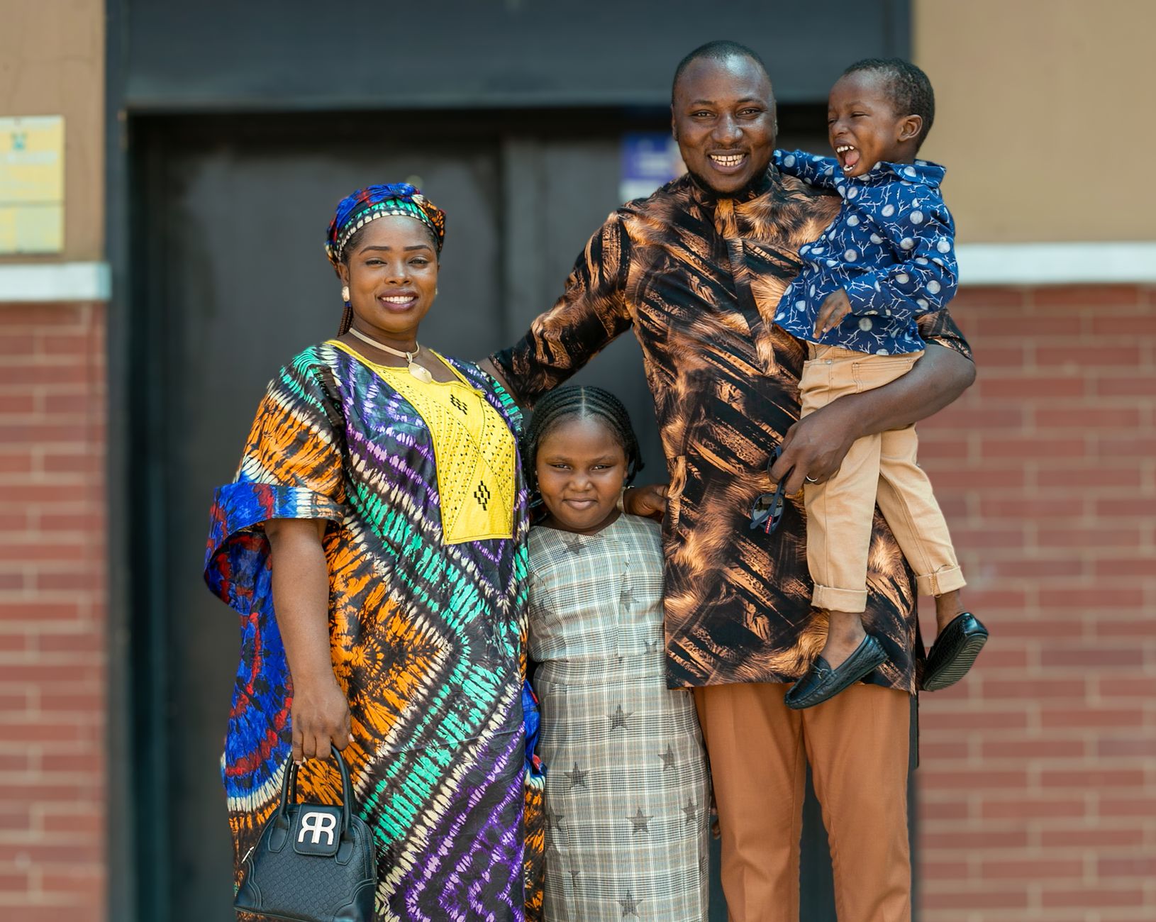 A joyful African family dressed in traditional clothing, smiling outdoors in Lagos, Nigeria.
